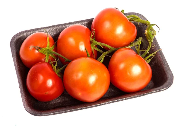 Tomates vermelhos maduros em uma bandeja de plástico escuro. sobre um fundo branco — Fotografia de Stock