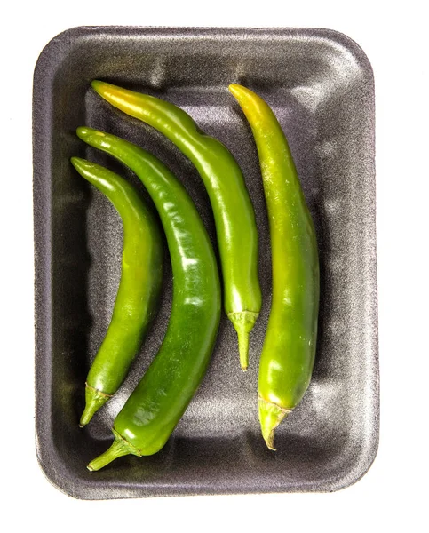 Chiles verdes en una bandeja de plástico negro. sobre un fondo blanco — Foto de Stock