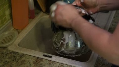 Genç adam mutfak lavabo deterjan ile Kettle yıkar, eller yakın