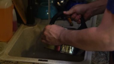 Genç adam mutfak lavabo deterjan ile Kettle yıkar, eller yakın