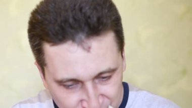 Bir iştah ile sevimli genç aç beyaz adam lezzetli ve sulu sandviç yiyor, dikkatle yakın çekim, yavaş hareket çiğneme
