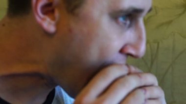 Bir iştah ile sevimli genç aç beyaz adam lezzetli ve sulu sandviç yiyor, dikkatle yakın çekim, yavaş hareket çiğneme