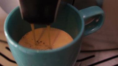 Kahve makinesi taze lezzetli ve aromatik sabah kahvesi hazırlar, buzlu mavi bir kupa içine dökülmüş, yakın çekim