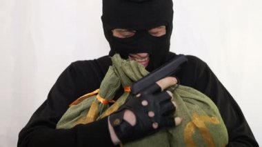 Genç beyaz hırsız Balaclava ve silah bir sırıtma ve zevk ile çalıntı torba para yakın çekim kucaklayan