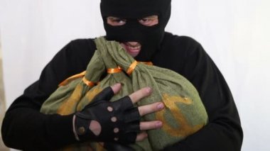 Genç beyaz hırsız Balaclava ve silah bir sırıtma ve zevk ile çalıntı torba para yakın çekim kucaklayan
