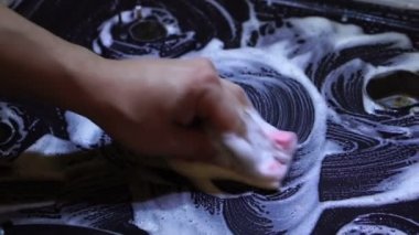Mutfakta genç bir adamın elleri gazlı sobayı yıkayıp köpük deterjanlı sünger ile yakın çekim