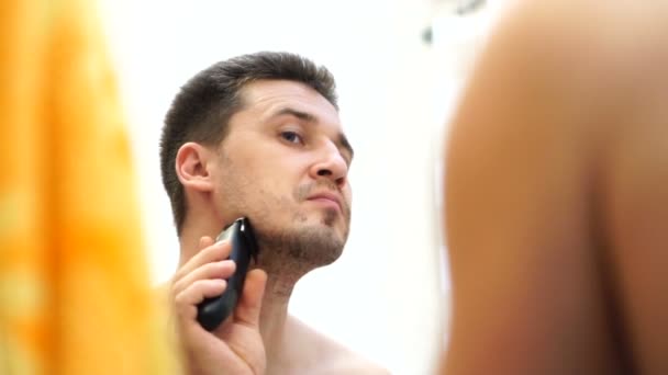 Young Handsome Caucasian Man Shaves Electric Razor Looking Reflection Mirror — Stock Video