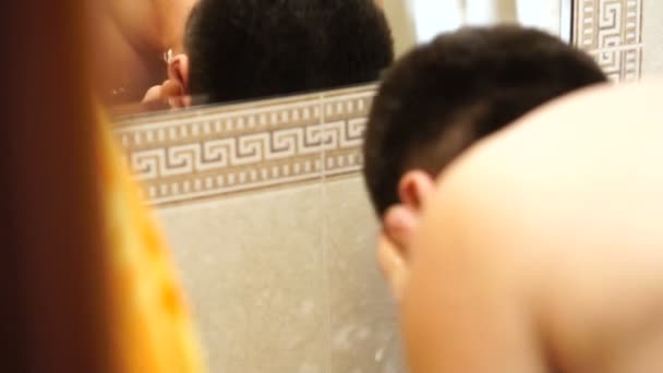 年轻的英俊的白种人男子洗脸在镜子反射 — 图库视频影像