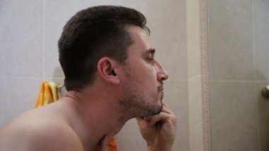 Genç yakışıklı beyaz adam bir diş fırçası ile ayna yansıma içine bakarak dişlerini fırçalama, yakın çekim