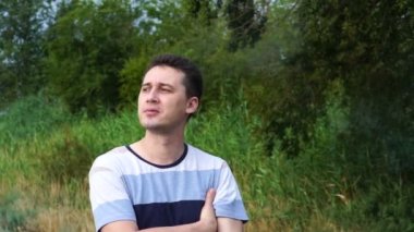 Genç yakışıklı beyaz adam nehir arka plana karşı bir sigara sigara, yakın çekim