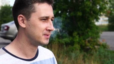 Genç yakışıklı beyaz adam nehir arka plana karşı bir sigara sigara, yakın çekim