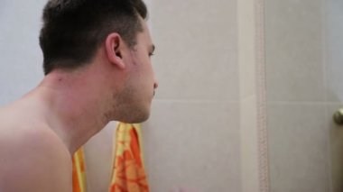 Genç yakışıklı beyaz adam tıraş için inlemek köpük uygular ve ayna yansıması içine bakıyor, yakın çekim