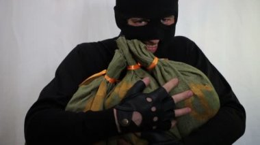 bir sırıtma ile Balaclava Genç beyaz hırsız ve zevk para çalıntı çanta ile kucaklayan yakın çekim