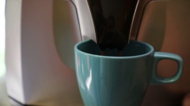 Kahve makinesi taze lezzetli ve aromatik sabah kahvesi hazırlar, buzlu mavi bir kupa içine dökülmüş, yakın çekim