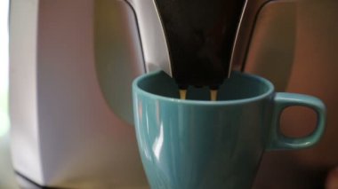 Kahve makinesi taze lezzetli ve aromatik sabah kahvesi hazırlar, buzlu mavi bir kupa içine dökülmüş, yakın çekim