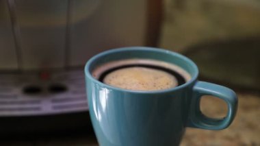 Buzlu, canlandırıcı taze demlenmiş sabah kahvesi mavi bir camdan dönüyor, yakın çekim