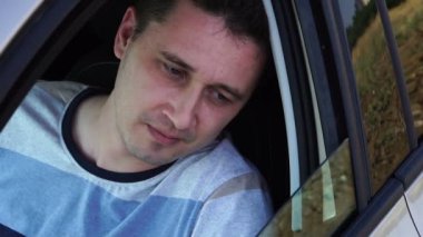 Genç üzgün Kafkas adam düşüyor ve yükselir gibi bir arabanın yan penceresine bakıyor, yakın çekim