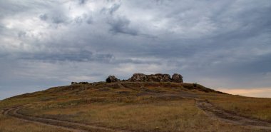 Bulutlu bulutlu bir gökyüzünün arka planında kayalık bozkır manzarası