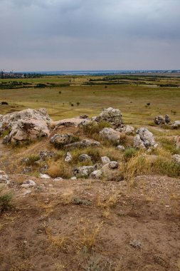 Bulutlu bulutlu bir gökyüzünün arka planında kayalık bozkır manzarası
