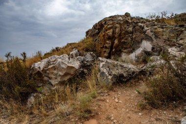 Bulutlu bulutlu bir gökyüzünün arka planında kayalık bozkır manzarası