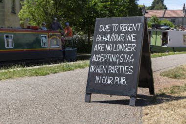 BATH, UK - JUNE 30, 2018 : A chalkboard sign outside a public house on the Kennet and Avon Canal notifying stag and hen parties they are no longer allowed entry due to recent bad behaviour. clipart