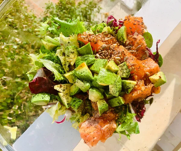 Yeşil salata, avokado, somon ve tohumlarla hazırlanmış sağlıklı ve taze bir yemek.
