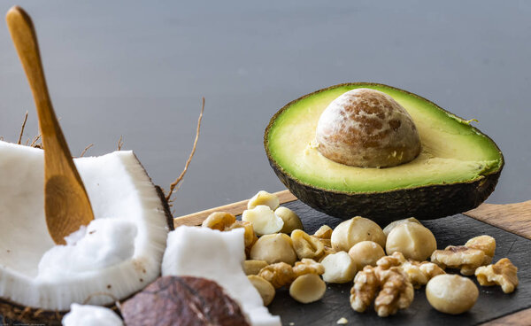 Крупный план кетогенной пищи: кокосовое и кокосовое масло, авокадо. орехи и орехи макадамии
