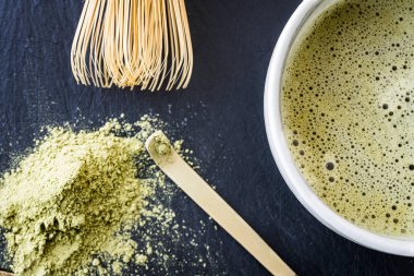 Bir kupa, bambu whist, bambu kaşığı ve yeşil çay tozu taze yapılmış matcha yeşil çay yakın