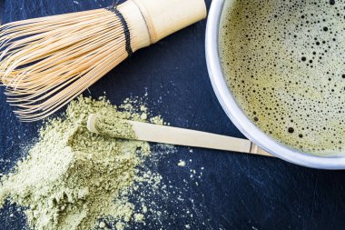 Bir kupa, bambu whist, bambu kaşığı ve yeşil çay tozu taze yapılmış matcha yeşil çay yakın