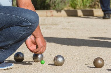 Senior people measuring distance in petanque game in a park outside clipart