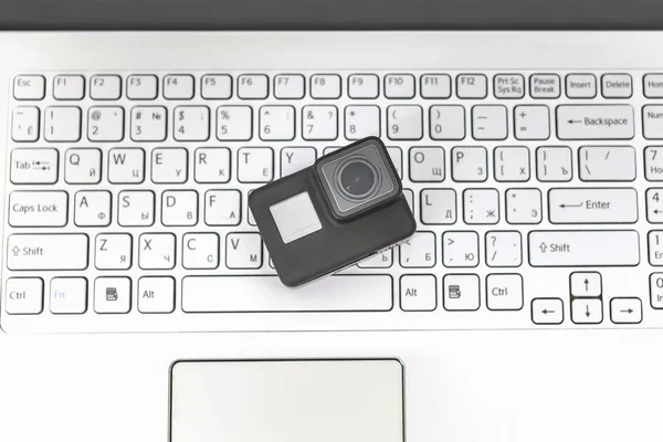 Action-camera on the background of a white laptop keyboard.