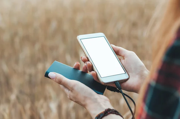 Mock Up del teléfono y el banco en la mano de una chica, sobre el fondo de un campo amarillo . —  Fotos de Stock