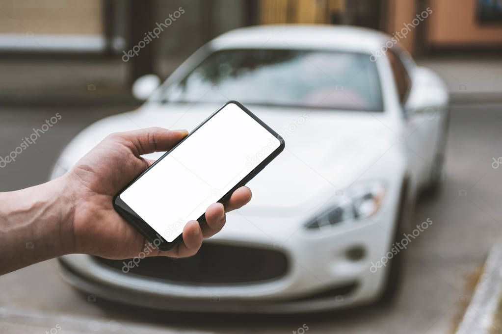 Mock Up Smartphone in man's hand, in the background a white car.