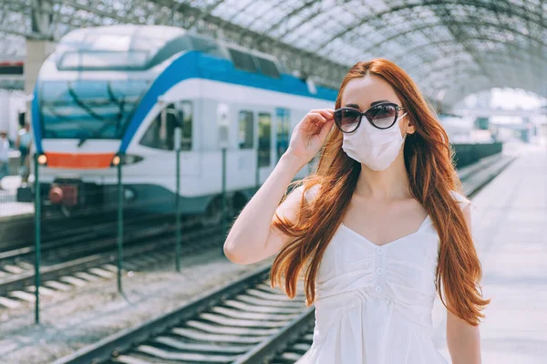 Cerrahi maskeli bir kadın koruma altında, havaalanı tren istasyonunda yürüyen bir kadın hastaneye gidip geliyor.