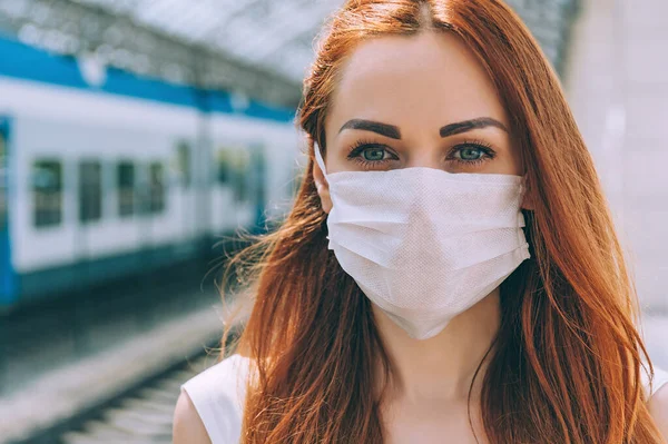 Merkezde, tıbbi maskeli bir kız. Modern bir trenin arka planına karşı.
