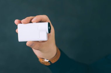 Adamın biri elinde beyaz aksiyon kamerasıyla özçekim videosu çekiyor. Siyah bir arkaplanda