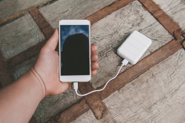 Akıllı telefon ve Güç Bankası 'nı genç bir adamın elinde kurgula. Eski bir göğsün arka planına karşı