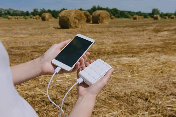 Akıllı telefon ve Güç Bankası 'nın Mock Up' ı, bir kızın elinde. samanlığı olan bir alanın arka planına karşı.