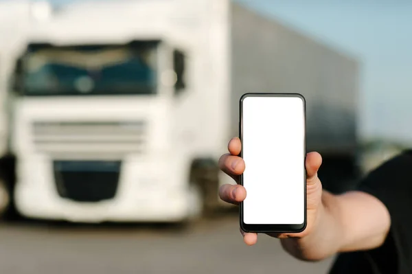 Bir adamın elinde akıllı telefon taklidi yapmak gibi. Kamyonların arka planına karşı. Lojistik kavramı