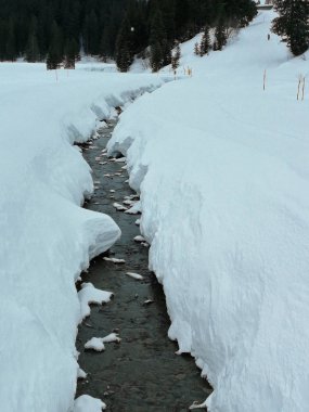 Karla kaplı vadide akan dere. Hoch-Ybrig, İsviçre.
