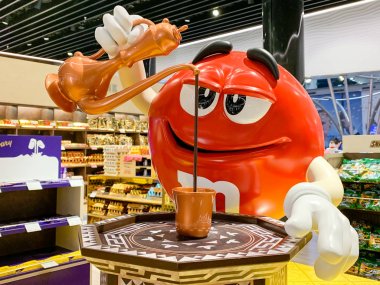 M&M maskot figürü bir kupaya Türk kahvesi döküyor. Farklı bölgeler ve ülkeler için şirket Mars şeker reklam adaptasyonu. İstanbul, Türkiye - Nisan 2019