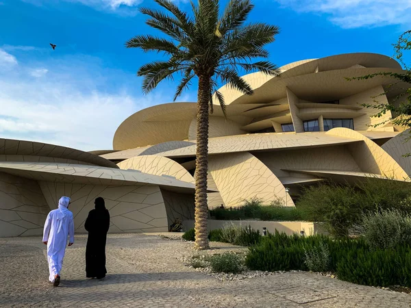 Museo Nacional de Qatar con pareja árabe no identificada caminando, Doha. El museo tiene forma de rosa del desierto y es de nueva construcción . —  Fotos de Stock