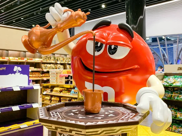 Figura mascota M & M vertiendo café turco en una taza. Adaptación de la publicidad de caramelos de la empresa MARS para diferentes regiones y países. Estambul, Turquía - abril 2019 — Foto de Stock