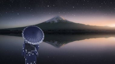 Girl with traditional dress look at Mount Fuji from Kawaguchi Lake in the evening 