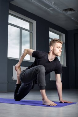 Genç adam spor salonunda geriniyor. Yoga pozisyonları üzerinde çalışıyorum.. 