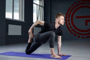 Genç adam spor salonunda geriniyor. Yoga pozisyonları üzerinde çalışıyorum.. 