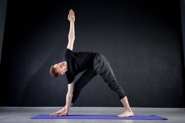 Genç adam spor salonunda geriniyor. Yoga pozisyonları üzerinde çalışıyorum.. 