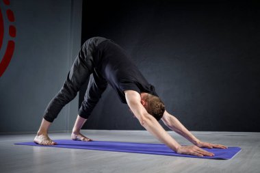 Genç adam spor salonunda geriniyor. Yoga pozisyonları üzerinde çalışıyorum.. 