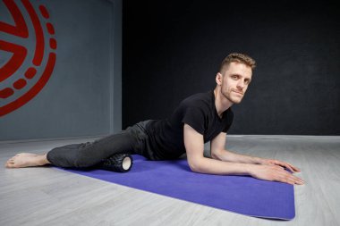 Genç atletik adam, iç kalça kaslarını esnetme egzersizi yapıyor..