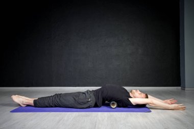 Genç atletik adam omurga kaslarını bigudiyle çalıştırıyor..